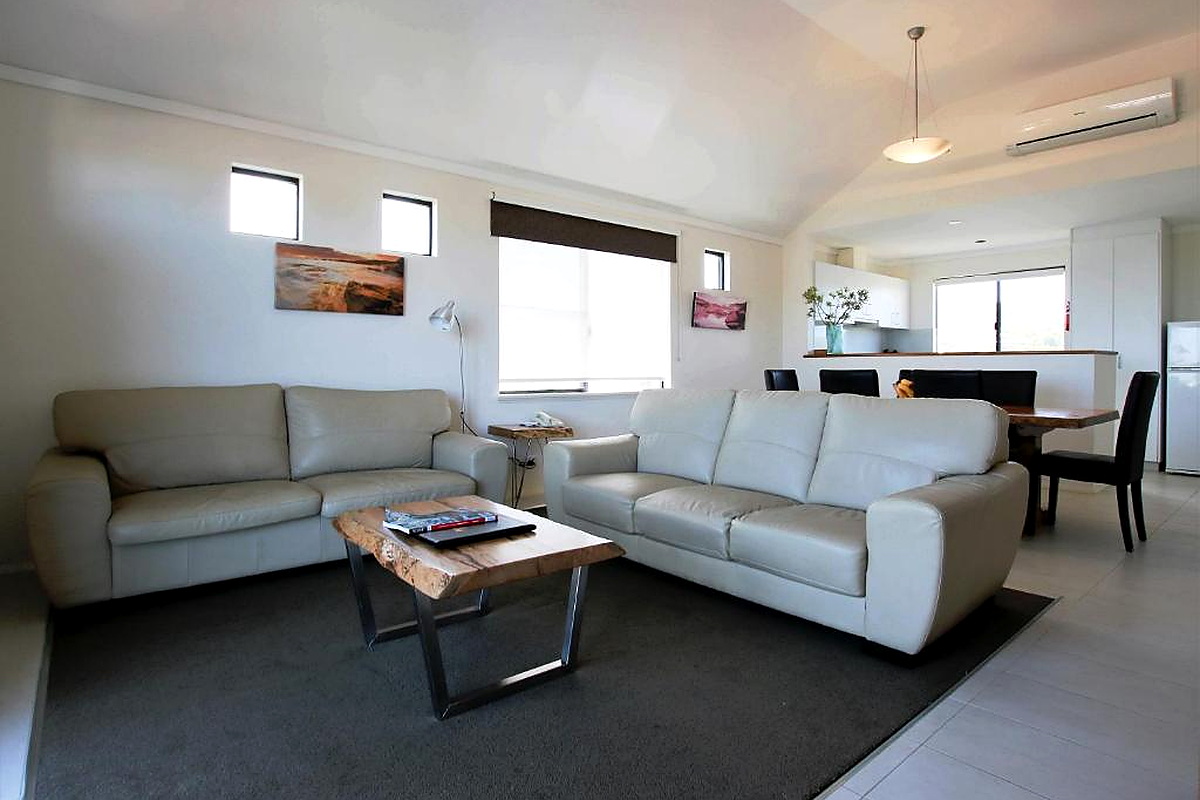 Modern open-plan living room with leather sofas and kitchen