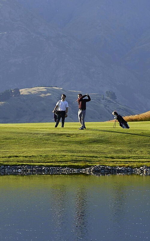 Two golfers playing on Millbrook Golf Club, Coronet Course beside lake