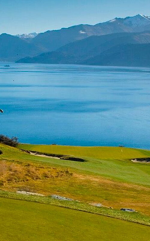 Two golfers playing on Jack's Point overlooking mountain lake