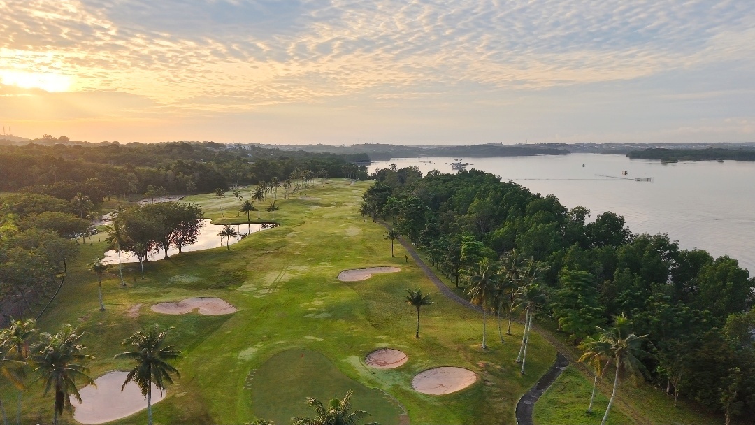 Aerial view of tropical atam Island Country Club beside calm river at sunset