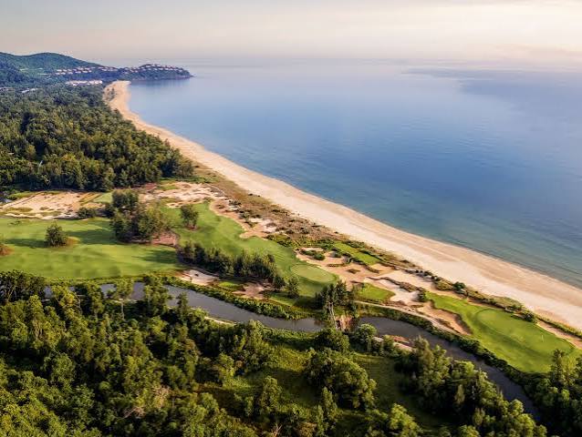 Aerial view of coastal golf course beside sandy beach