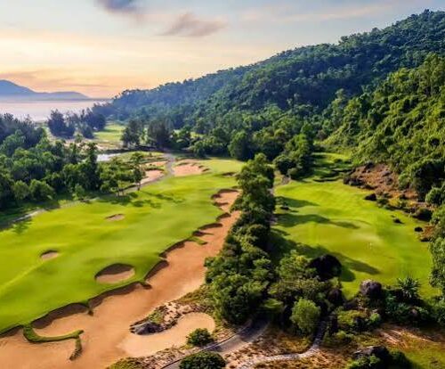 Aerial view of lush golf course nestled among forested hills