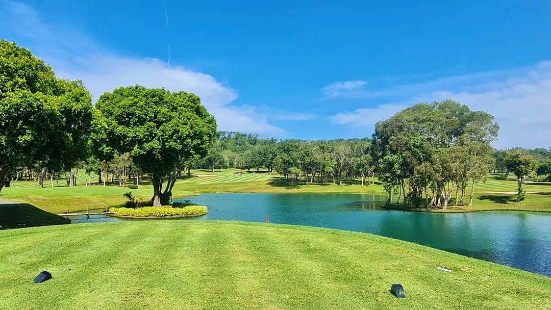 Lush green golf course with lake and blue sky