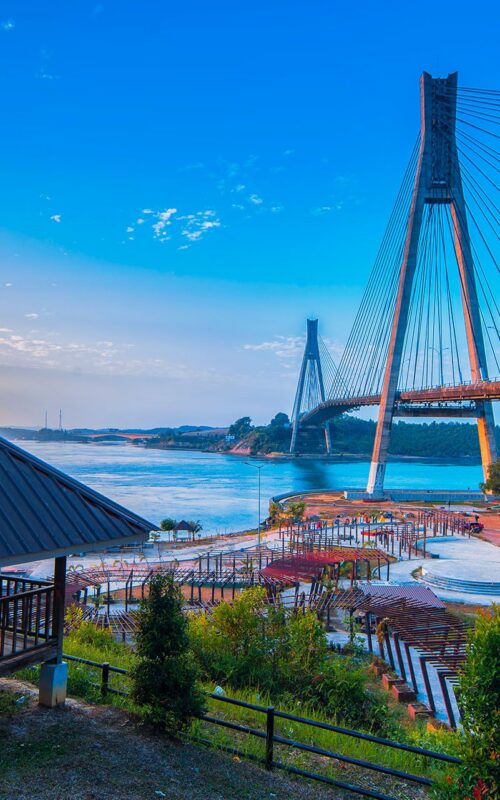 Cable-stayed bridge over river with gazebo at sunset