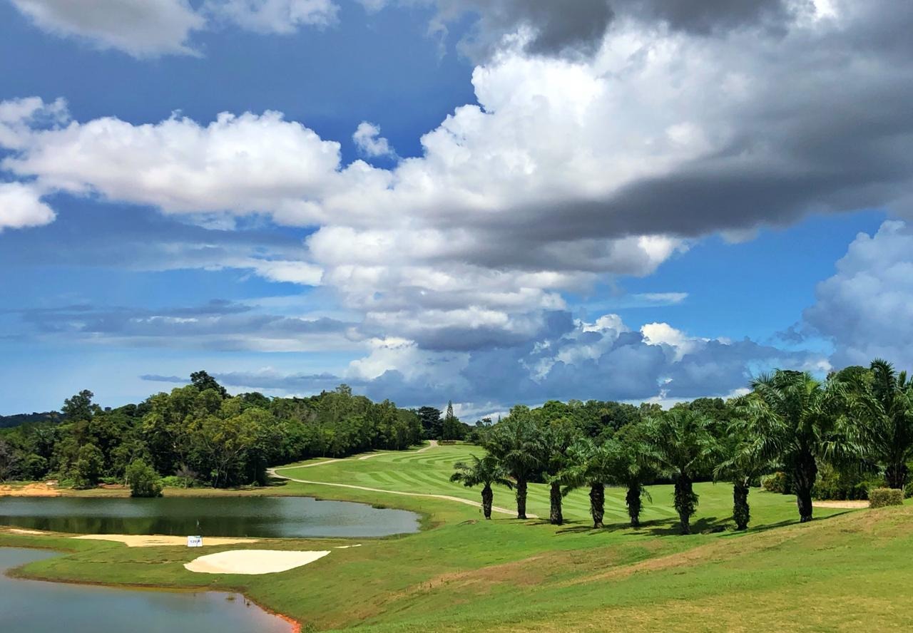 Tropical Palm Springs Golf & Country Club with water hazard, palm trees, and dramatic sky