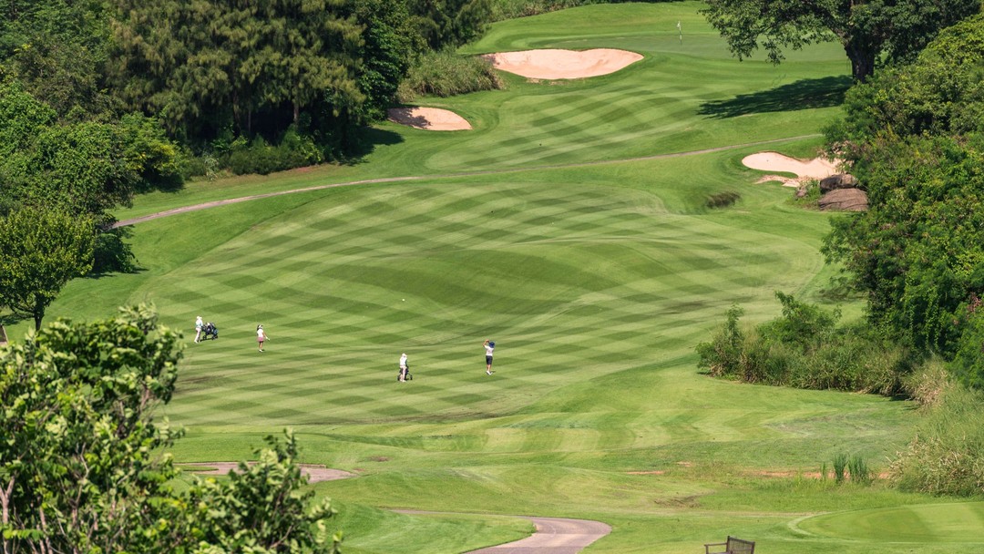 Golfers playing on a lush green Pineapple Valley Golf Club Hua Hin with sand bunkers