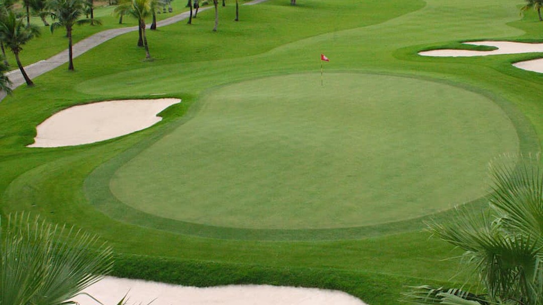 Lush Suwan Golf & Country Club green with red flag and bunkers. Play Suwan Golf & Country Club with Golfing Getaways
