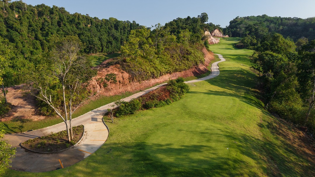 Aerial view of a lush Red Mountain Golf Club fairway through forested hills
